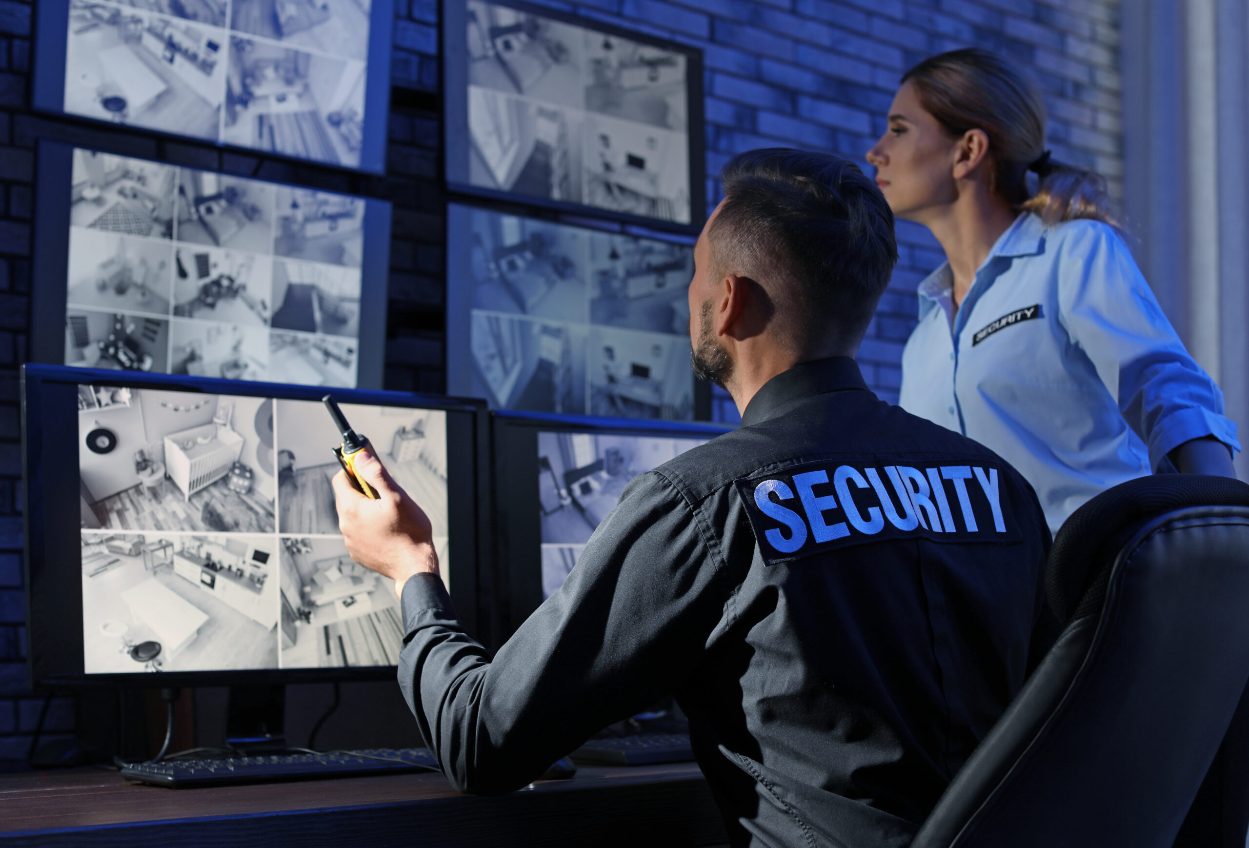 Stock image of two security guards looking at security screens - AW Precision